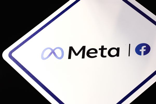 A sign shows the logo for Meta. On one side of the word is an infinity loop, while on the other side is the logo for Facebook, a white f inside a blue circle.